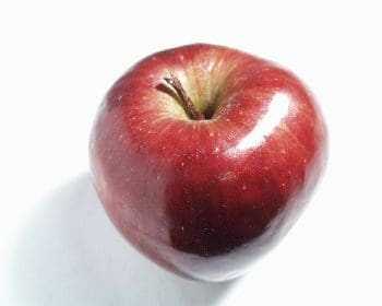 A red apple sitting on top of a table.