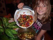 A girl holding a bowl of chopped vegetables