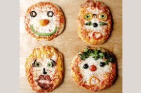 Four different pizzas with faces made of cheese and vegetables.