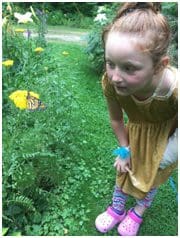 A little girl in yellow dress looking at butterfly.